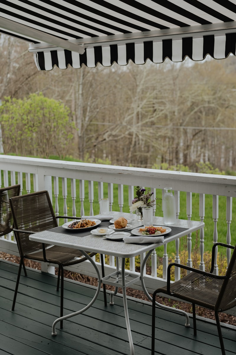 Black and white striped awning extended over a wooden deck dining set